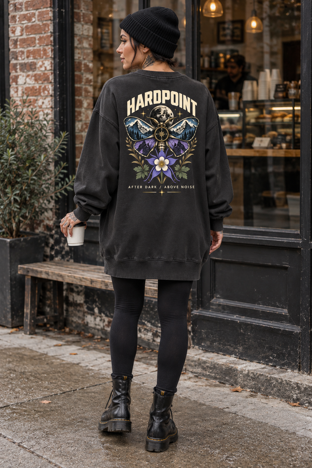 AI-styled lifestyle mockup of the HARDPOINT After Dark washed pullover dress, back view outside a coffee shop.