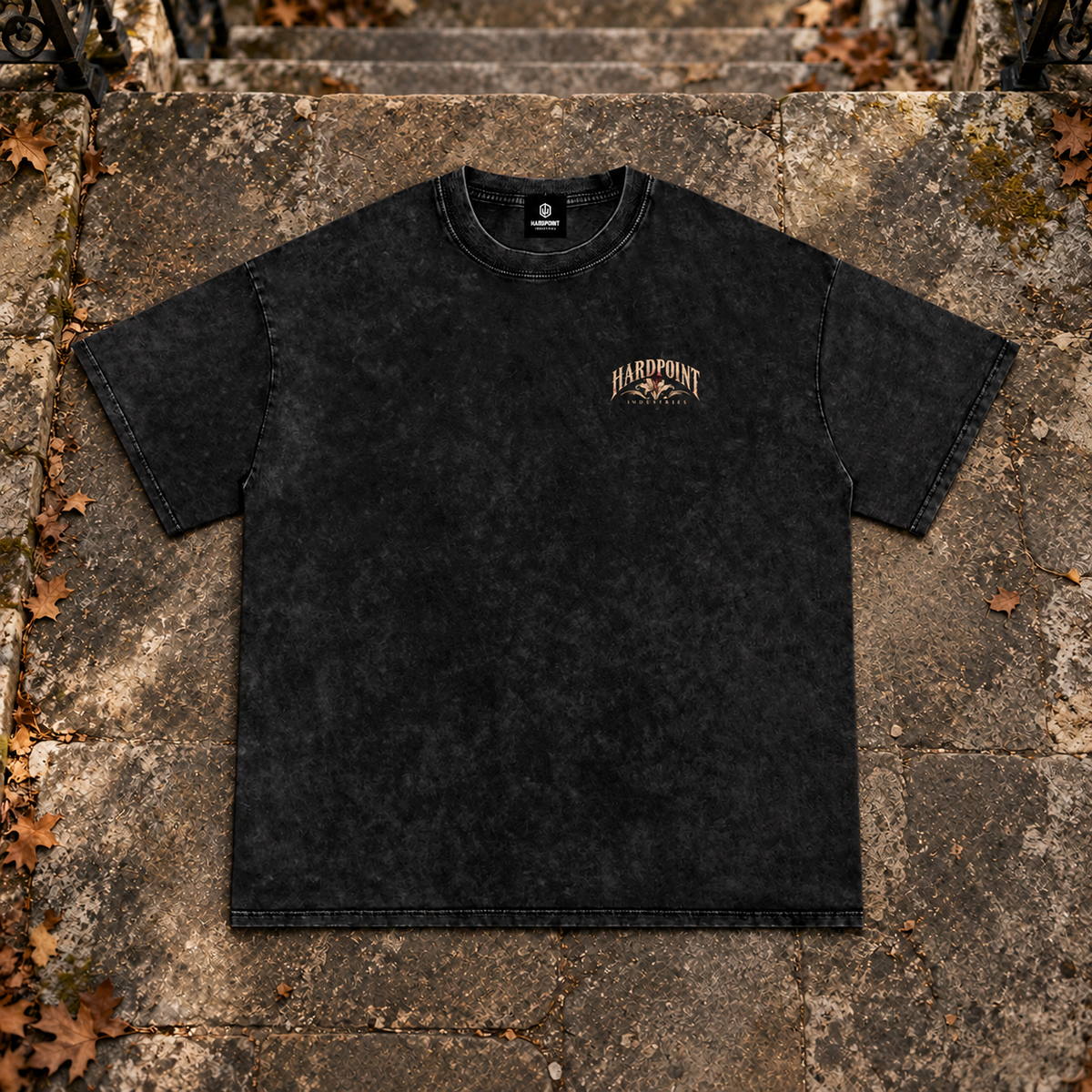 HARDPOINT Floral Blade Snow-Washed Oversized Tee, Black, front view on aged stone steps. AI-styled product mockup.