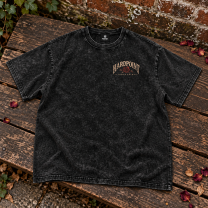 HARDPOINT Grenade & Roses tee, front view on a weathered garden bench. AI-styled product mockup.