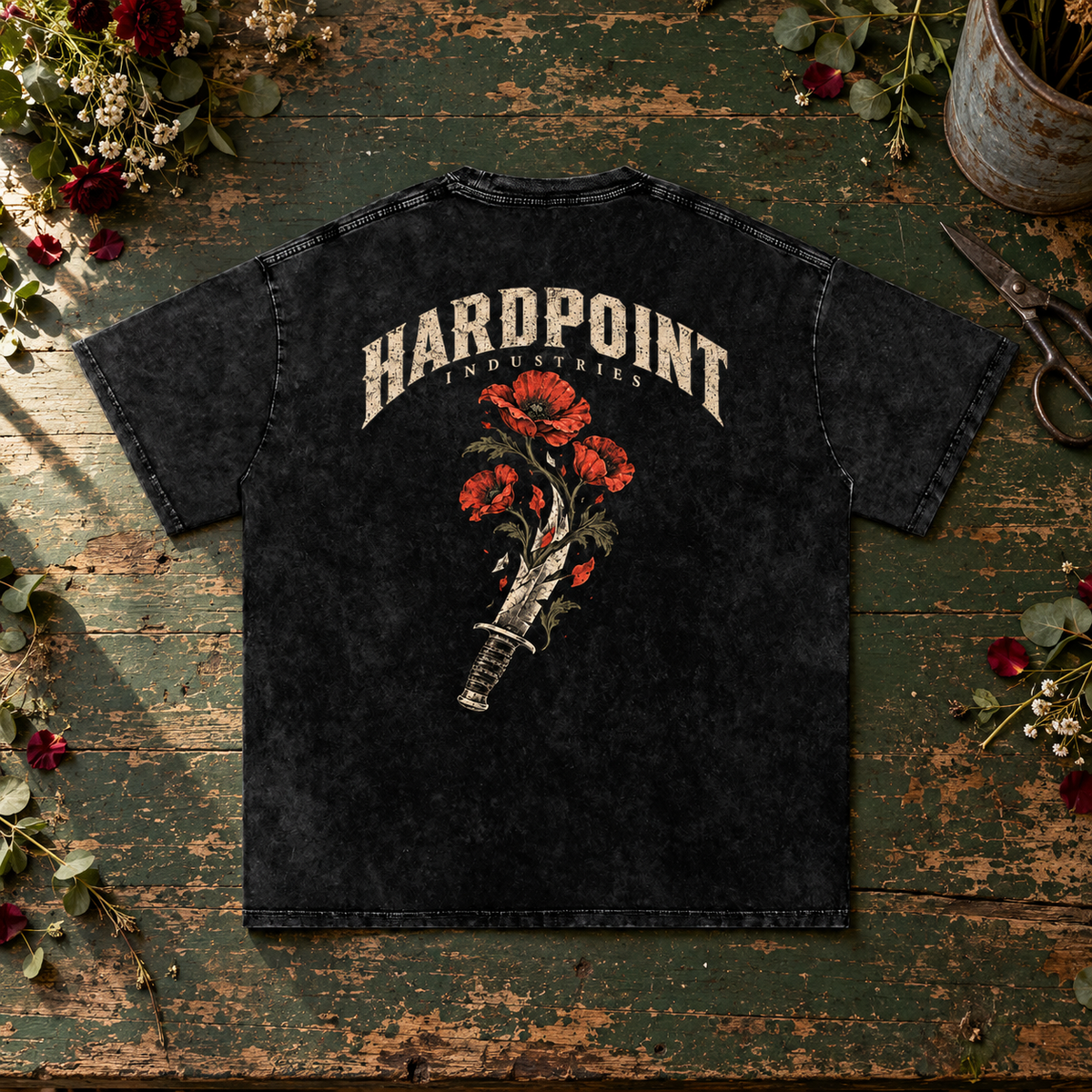 HARDPOINT Knife & Flowers tee, Black, back view on a green florist worktable. AI-styled product mockup.