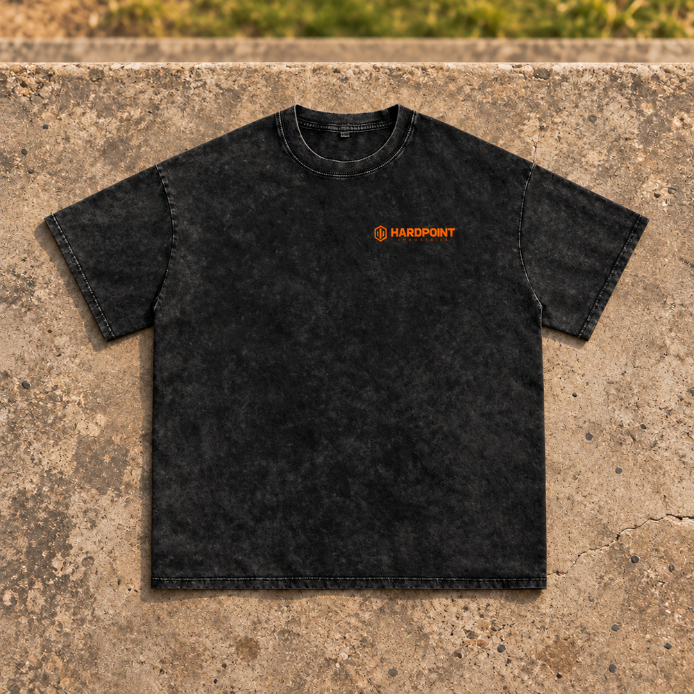 HARDPOINT Leave It All on the Field Snow-Washed Oversized Tee, Black, front view on sports-field concrete landing. AI-styled product mockup.