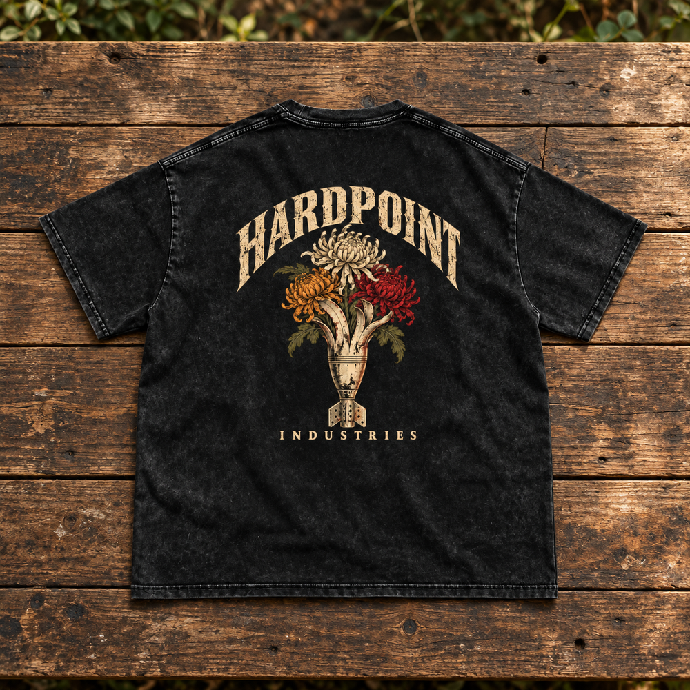 HARDPOINT Mortar Bouquet Snow-Washed Oversized Tee, Black, back view on weathered timber bench. AI-styled product mockup.
